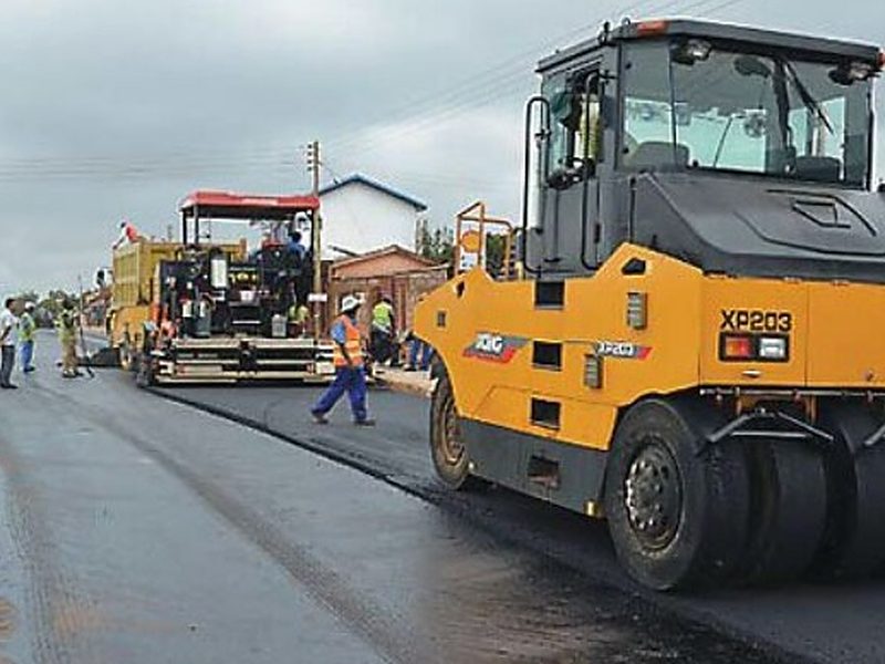 Road construction with a paver and pneumatic roller